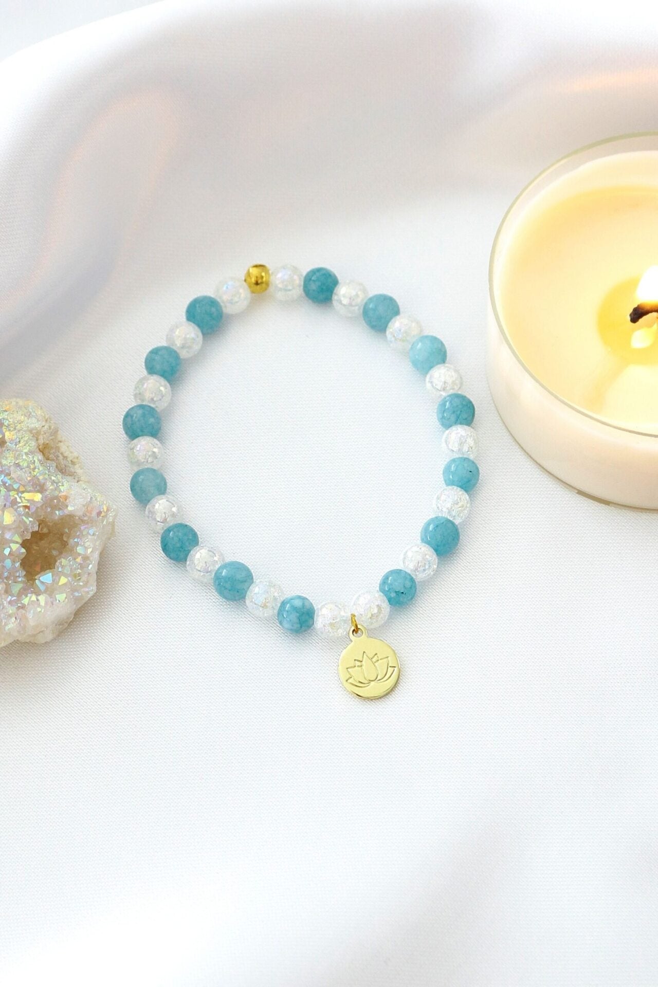 Ultramarine Birch aquamarine elastic bracelet with a 24K lotus flower charm, featuring smooth blue gemstones and elegant design.