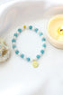 Ultramarine Birch aquamarine elastic bracelet with a 24K lotus flower charm, featuring smooth blue gemstones and elegant design.