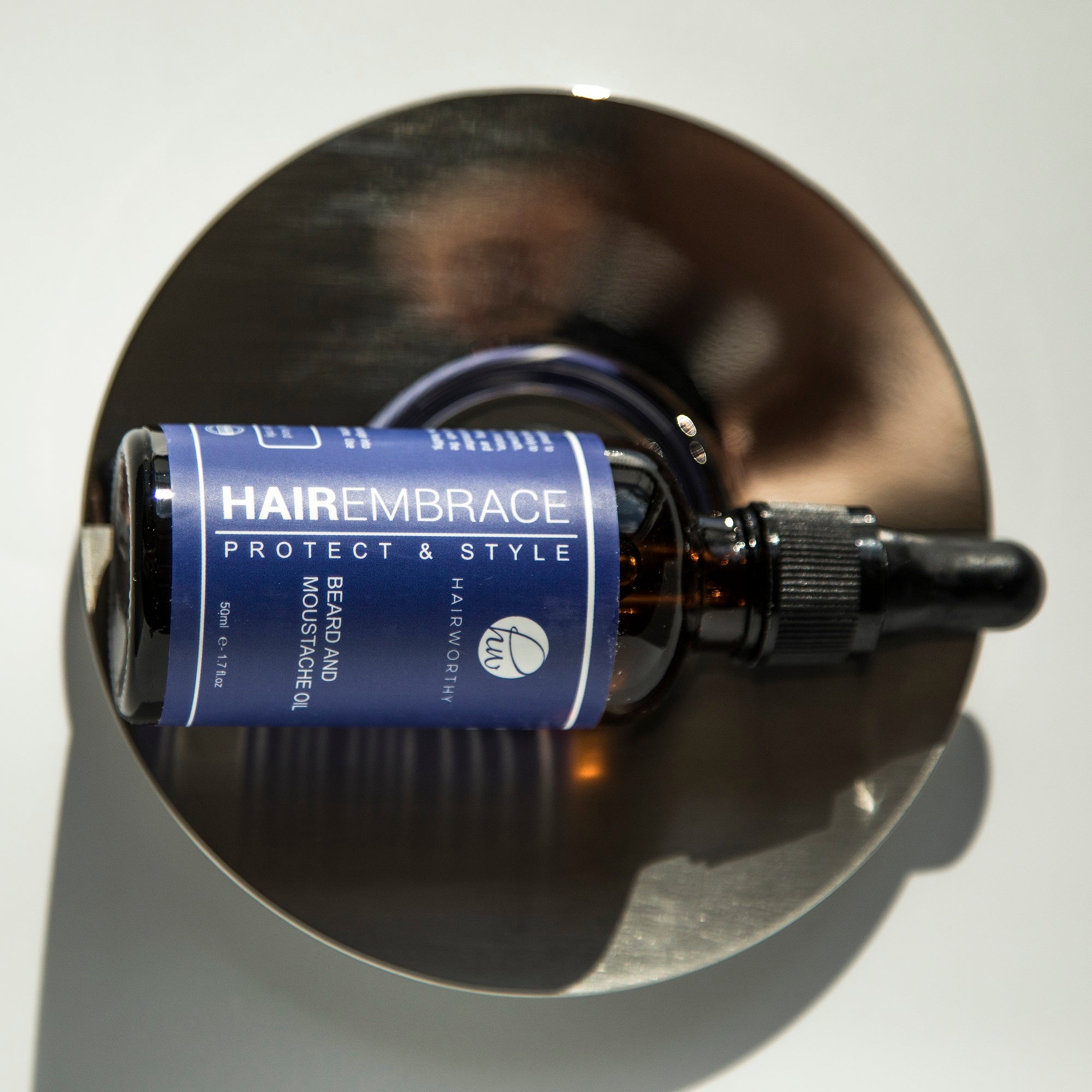 Black Sugarplum Hairworthy Hairembrace Beard Oil bottle, bath and beauty product with a sleek design and black cap.