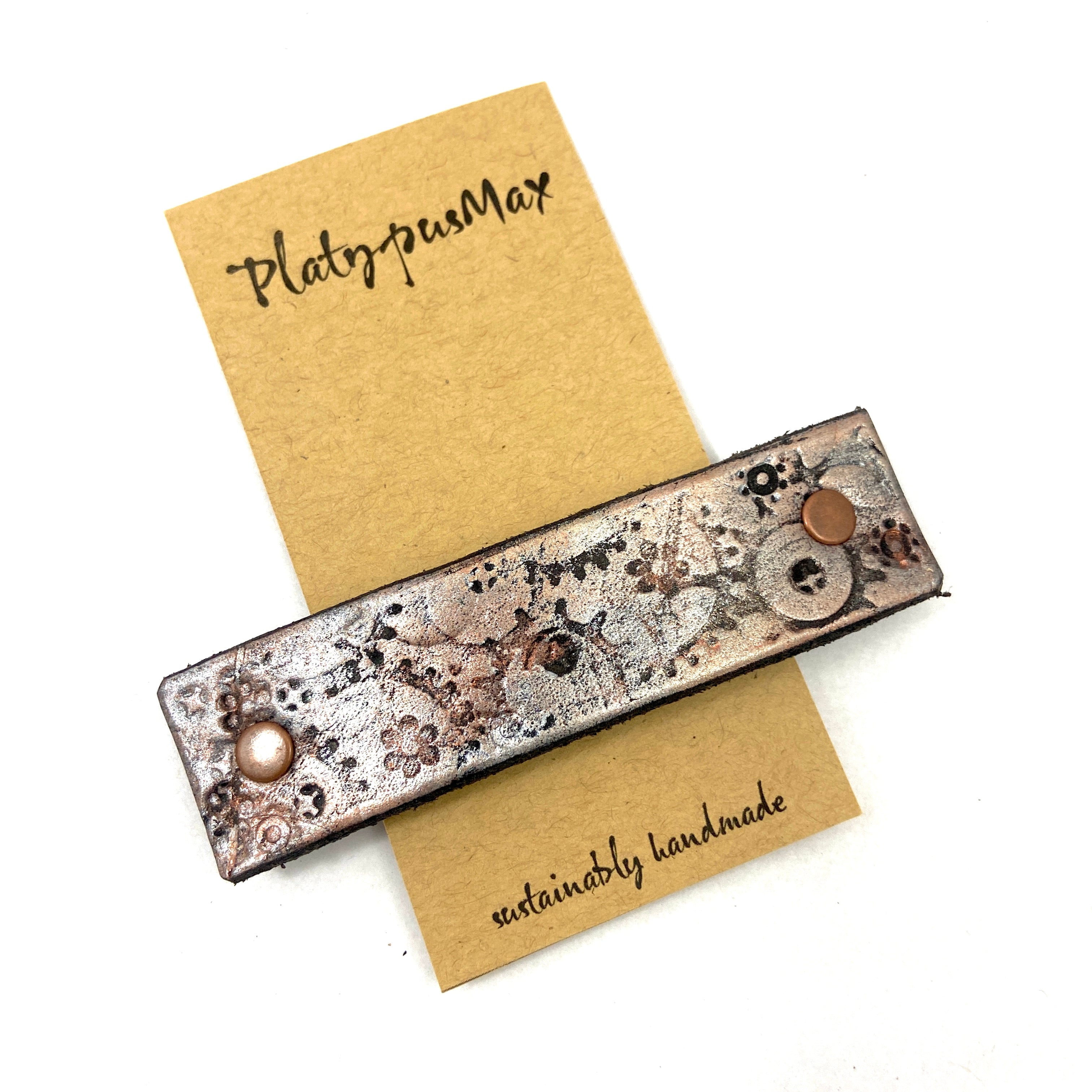Copper and silver metallic gears on stamped leather hair accessory, steampunk-inspired hairpiece by Orange Themis for unique hair styling.