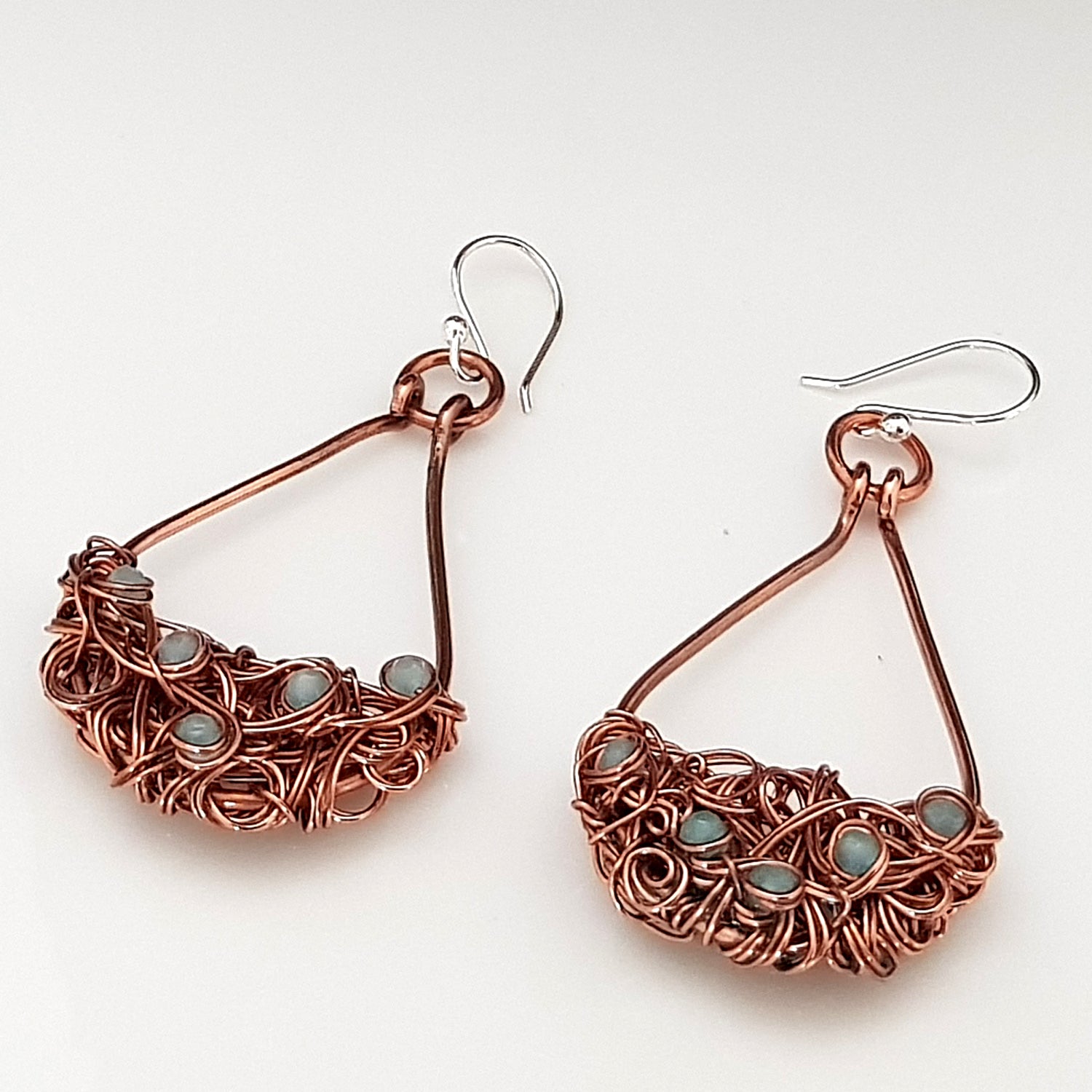Copper teardrop tangled earrings by Maroon Smudge with intricate design and warm metallic finish, hanging from earring hooks.