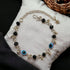 Gray Poseidon Fortune’s Shield Evil Eye bracelet featuring a silver and blue beaded design with a protective evil eye charm.
