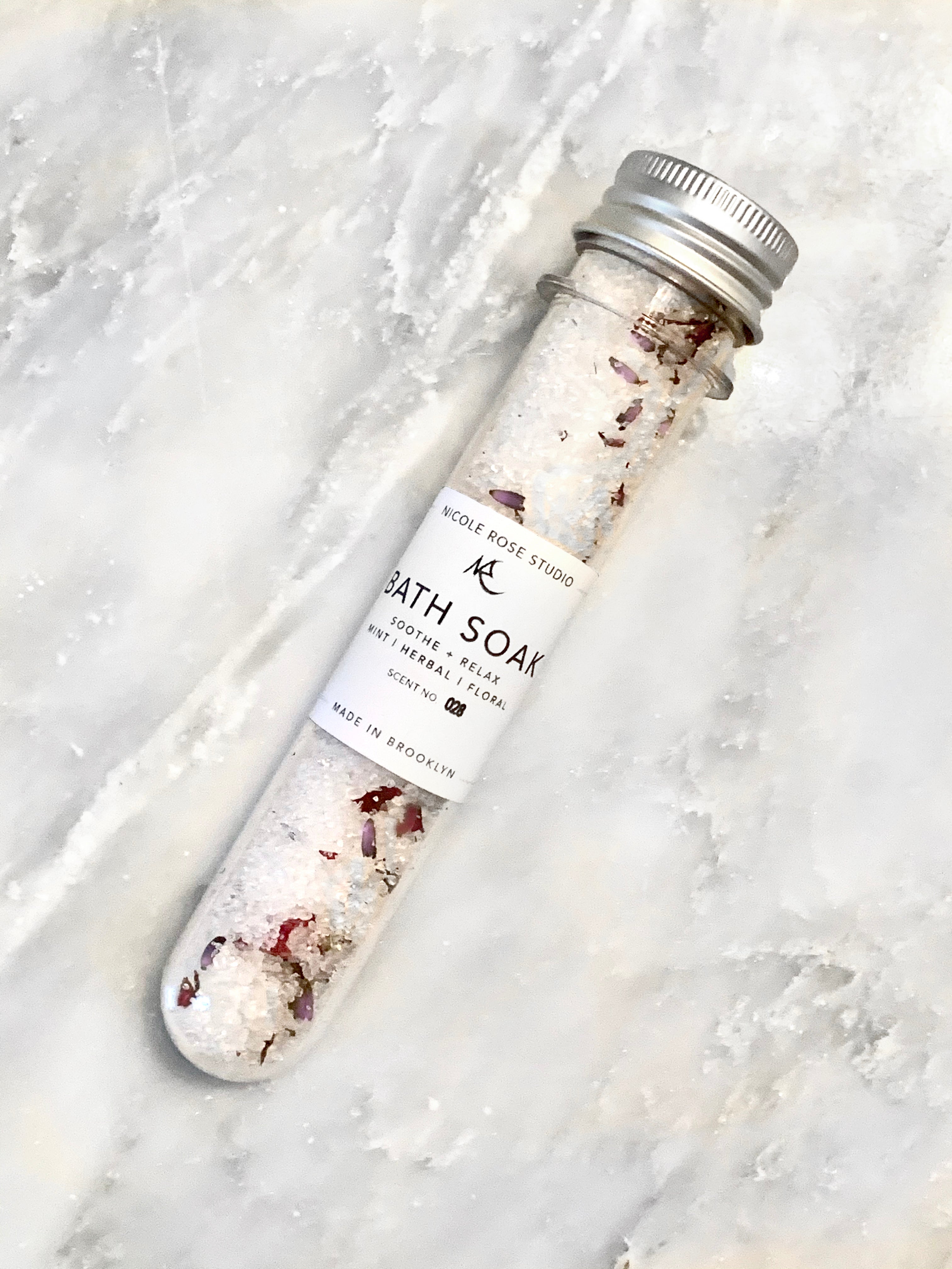 Indigo Poseidon Soothe + Relax Bath Soak Shooter with calming herbs and bath salts in a clear glass jar, perfect for soothing baths.