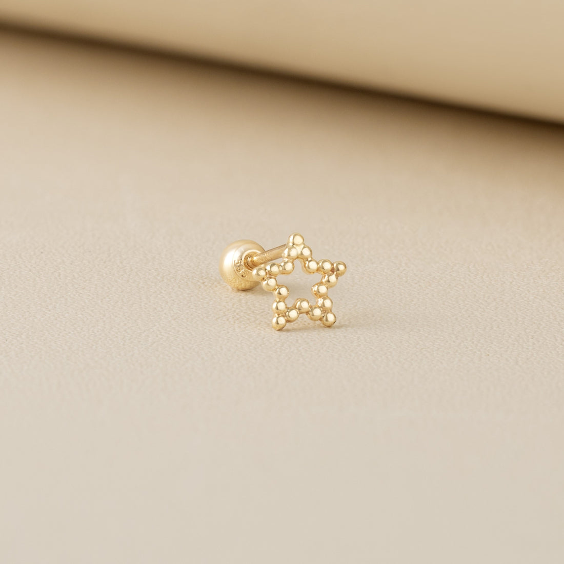14K solid gold Stella piercing earrings by Blue Chrysippus featuring a star-shaped design.