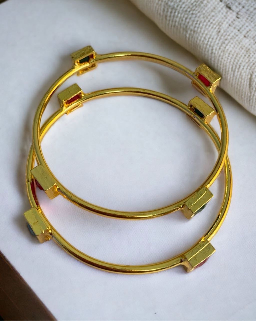Gold-plated Indian bangles with intricate traditional designs, stylish jewelry by Gray Poseidon displayed on a white background.