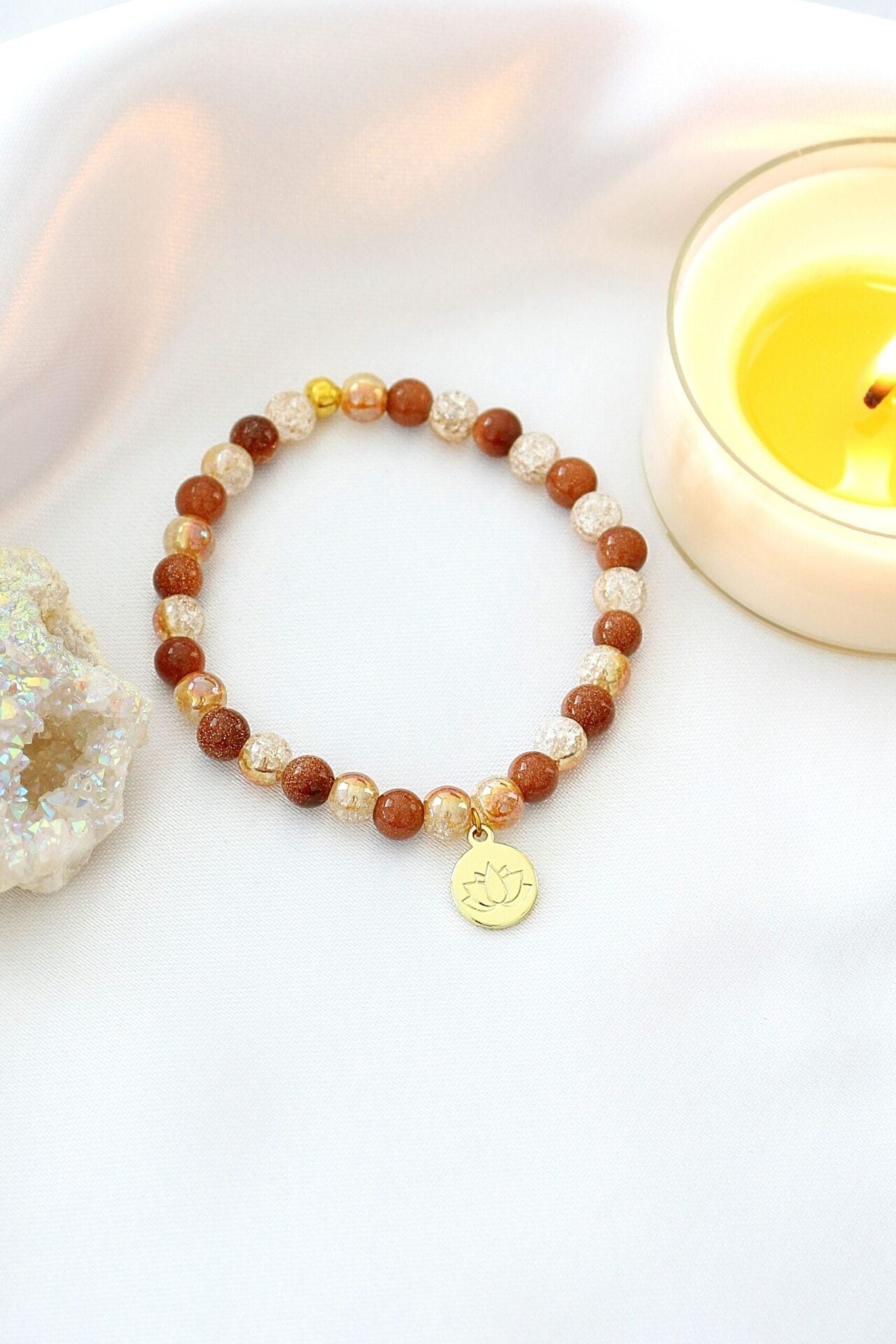 Goldstone elastic bracelet by Ultramarine Birch with a 24K lotus flower charm and smooth goldstone beads.
