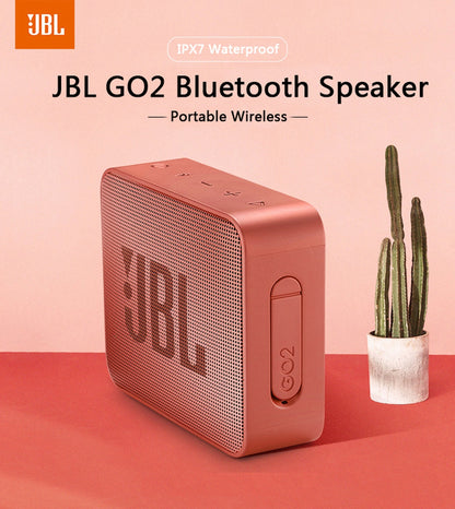 White Eucalyptus waterproof wireless Bluetooth speaker for pets, IPX7 rated, portable JBL GO2 style device in a pet-friendly setting.