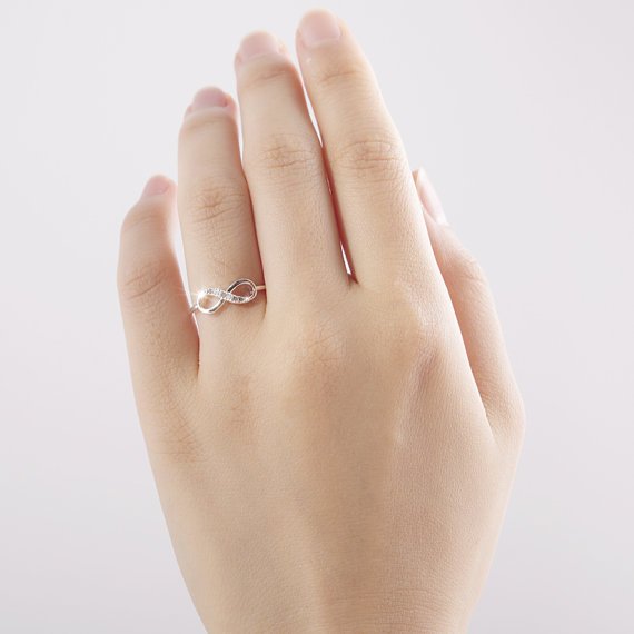 Silver infinity ring with rhinestone accents by Fuchsia Molly, showcasing a sleek, elegant design on a white background.