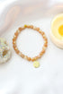 Sunstone elastic bracelet with 24K lotus flower charm by Ultramarine Birch, featuring vibrant orange sunstone beads and a gold lotus pendant.