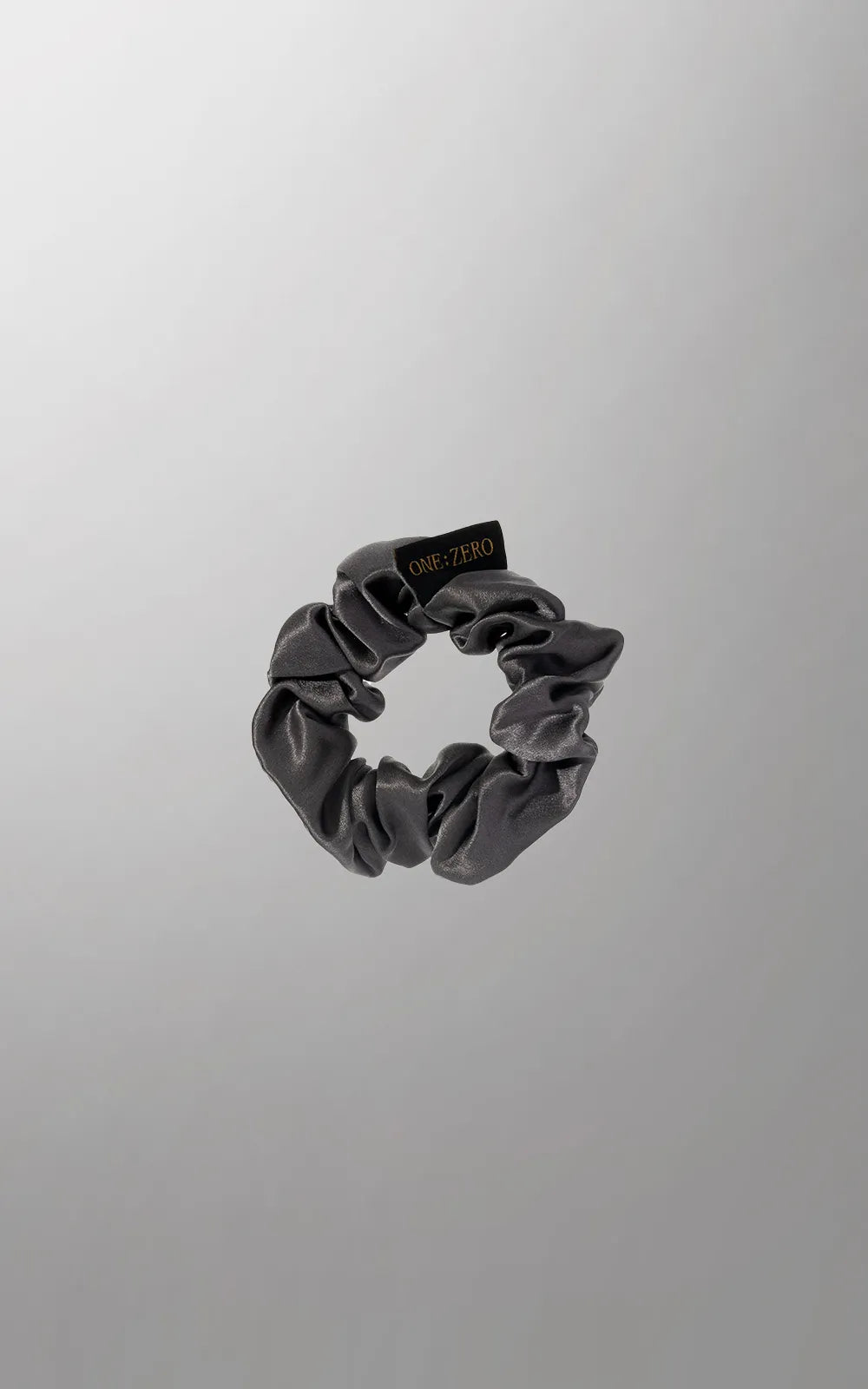 Silk hair ties by Burgundy Clover in gray, golden, and white, shown in medium and large sizes, arranged on a white background.