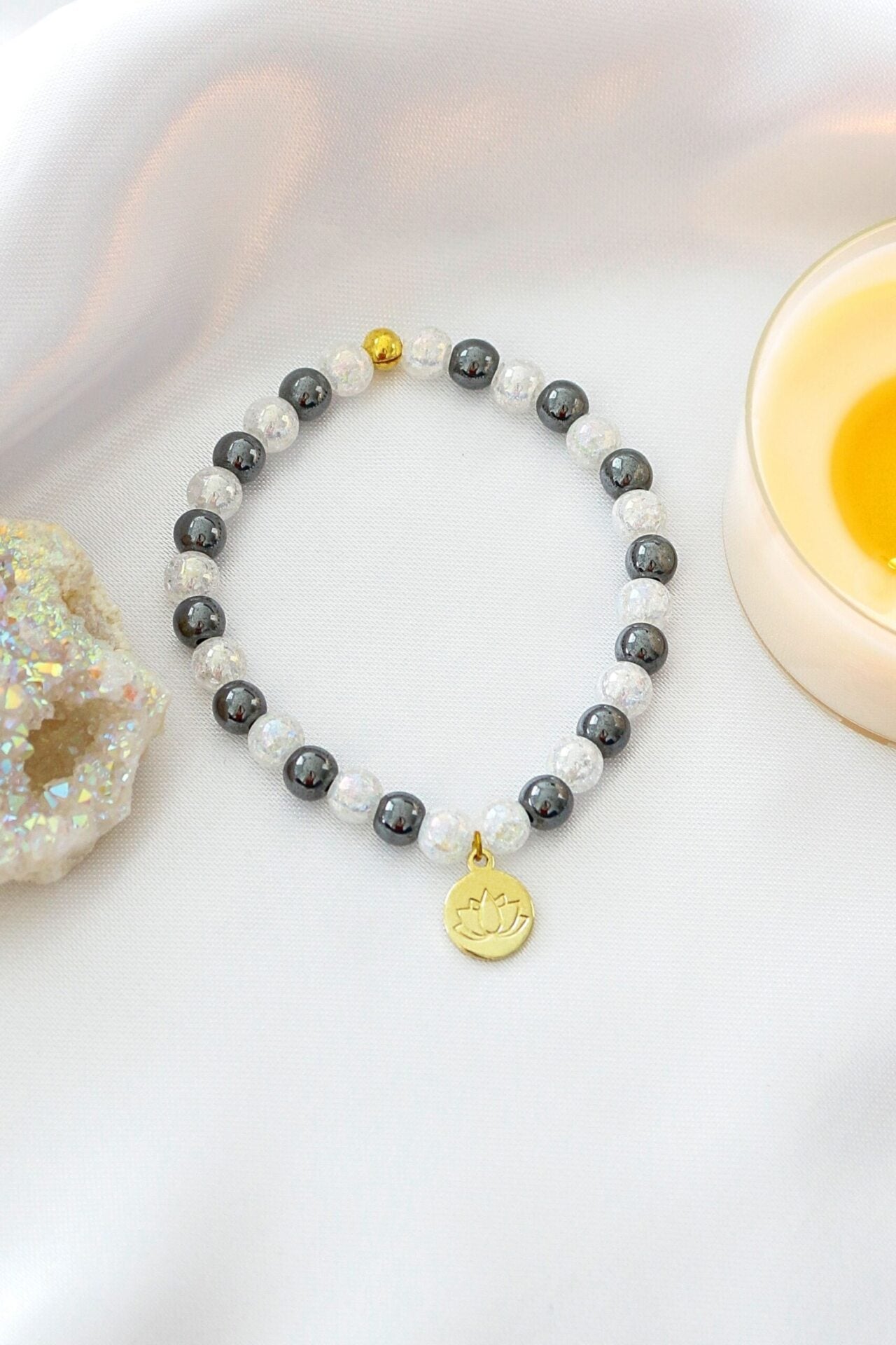 Hematite elastic bracelet with a 24K gold-plated lotus flower charm, designed by Ultramarine Birch.
