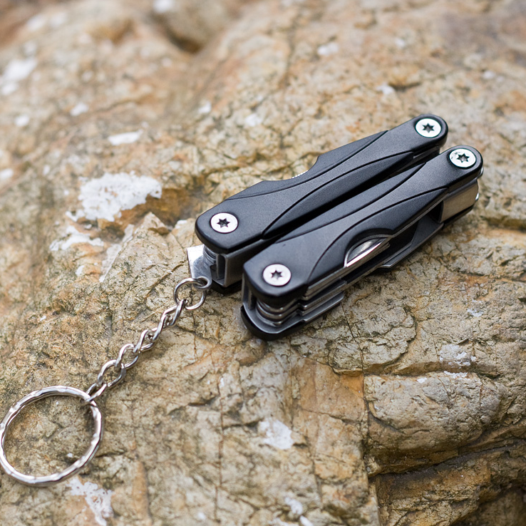 Fuchsia Molly outdoor multifunction camping tool with pliers, knife, screwdriver, and bottle opener on a camping table.