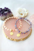 Ultramarine Birch rose quartz and amethyst elastic bracelet with a 24K lotus flower charm on a white background.