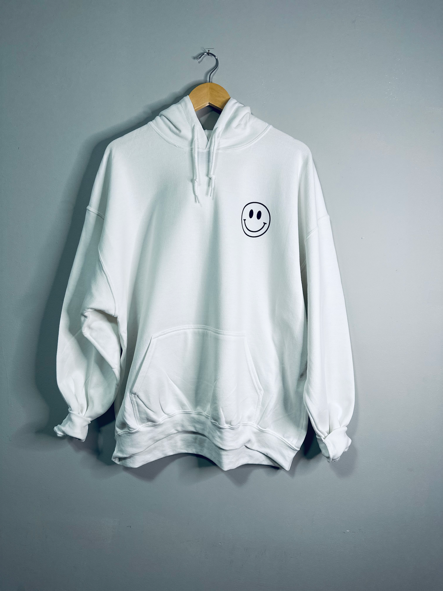 White hoodie from Emerald Ourea with "Dear Person Behind Me" text, casual sweater hoodie with front pocket and drawstrings.
