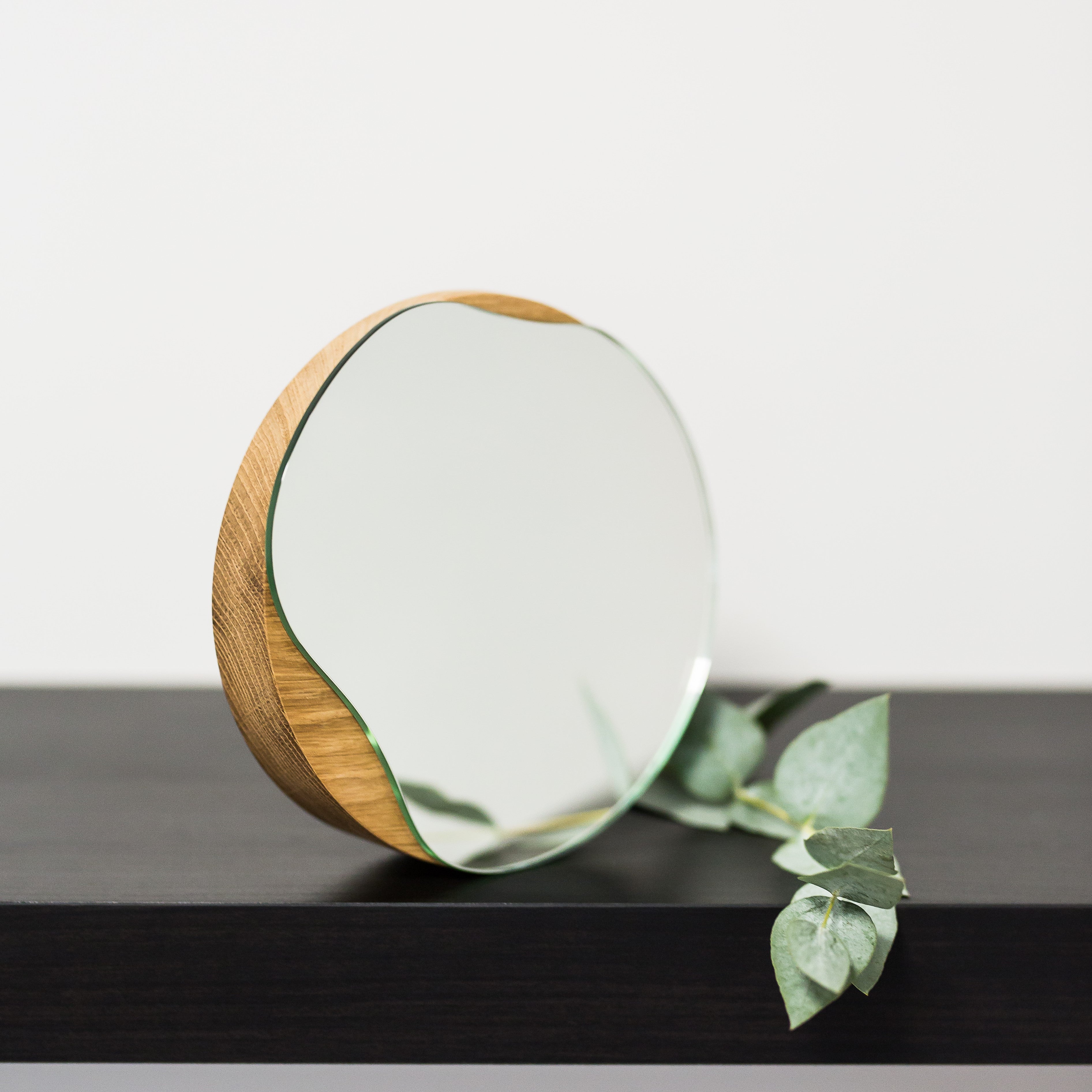 Biotite bathroom cosmetic round mirror with oak wood or black frame, reflecting a modern, stylish bathroom decor.