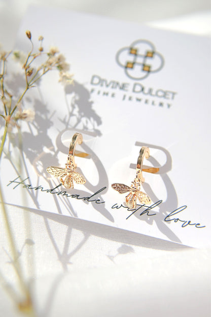 24 Karats gold bee hoop earrings by Ultramarine Birch, featuring detailed bee design on shiny gold hoops.