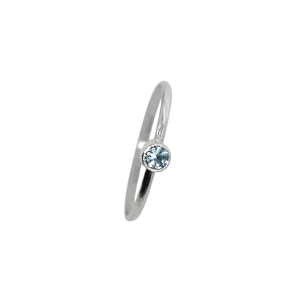 Sterling silver ring with a dainty blue topaz solitaire gemstone from Grey Clymene, featuring a sleek tube design.