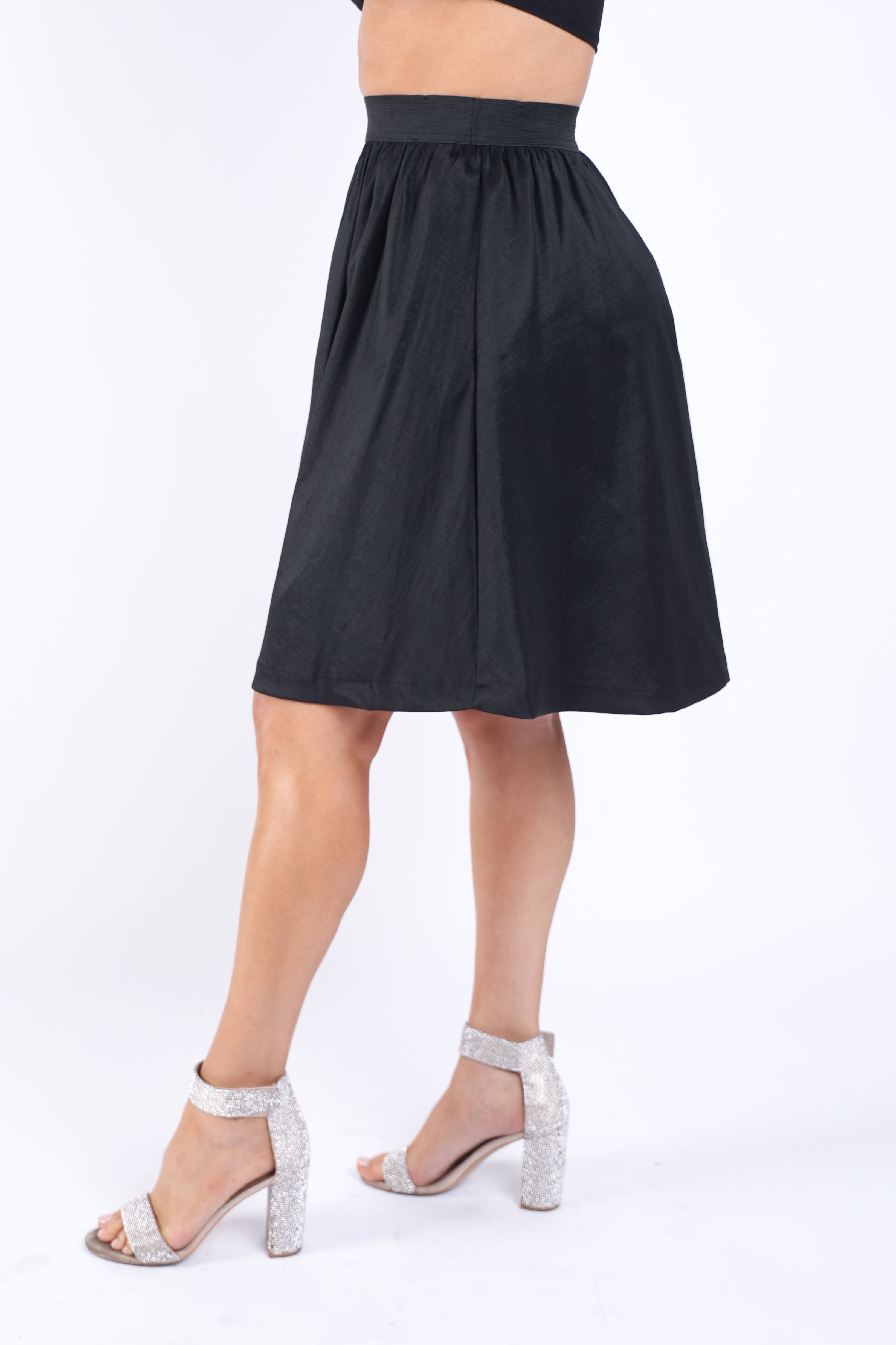 Black casual elastic high waist pleated midi flare skirt by Puce Juniper, shown with a flowing silhouette and pleated design.