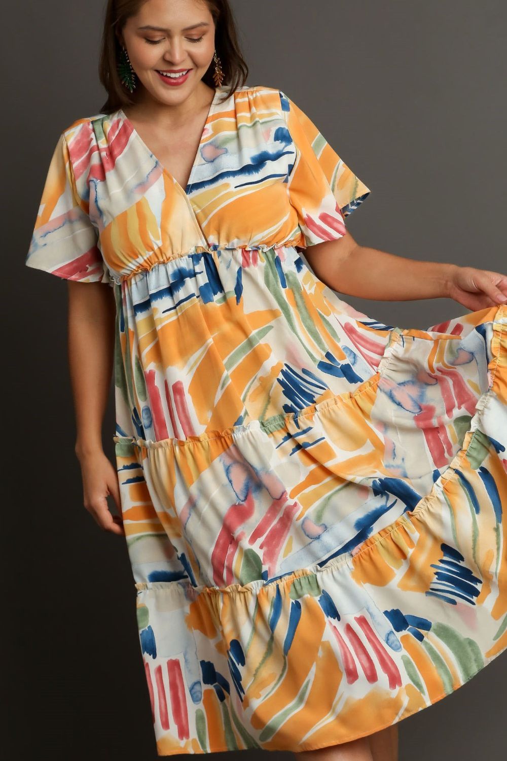 Colorful abstract print Umgee flutter sleeve tiered midi dress featuring frill details, styled with automotive-inspired design elements.