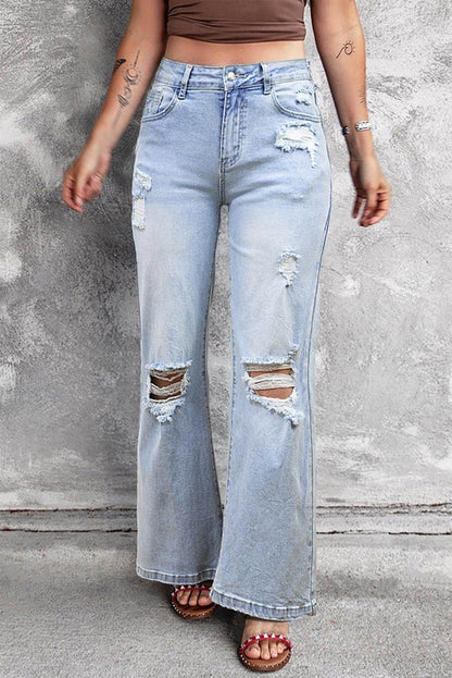 Carmine Juneberry Beau Blue vintage light wash distressed flare jeans hanging on a rack with frayed edges and faded denim.
