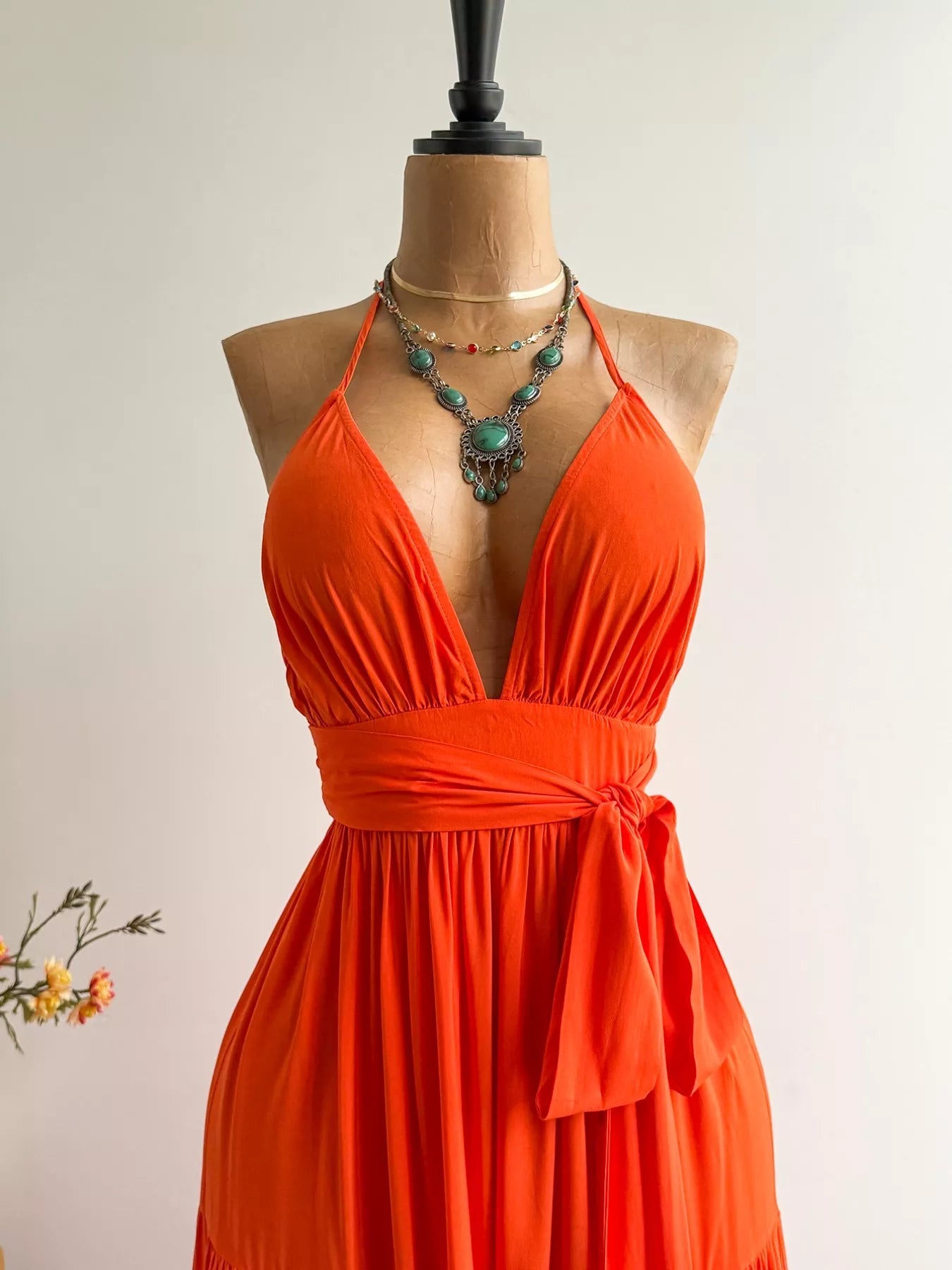 Halter neck tiered dress by Pear Daisy, displayed in a cozy home setting, showcasing flowing fabric and tiered design.