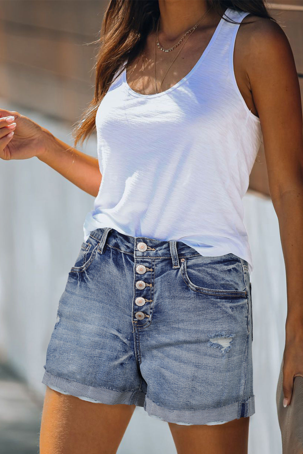 Distressed high-rise button fly denim shorts by Harlequin Daisy, showcasing frayed edges and classic denim texture.