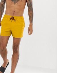 Gold Sky Felix swim shorts with a relaxed fit, shown hanging on a wooden surface with a casual summer vibe.