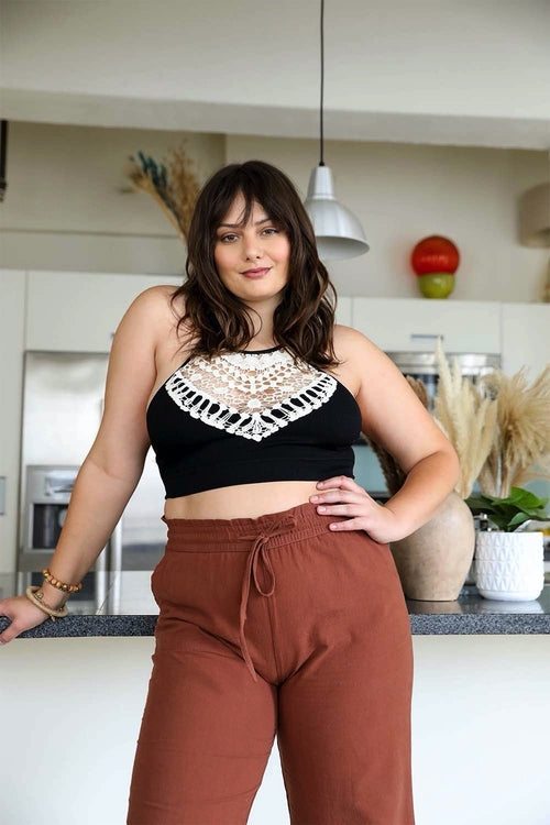 Black crochet lace bralette by Periwinkle Aether featuring a high neck, halter style, and cross-back design in lightweight, stretchy material.