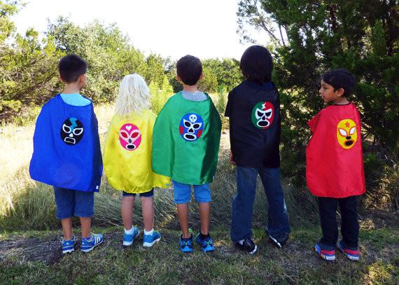 Colorful Mexican wrestler capes for kids, featuring red and green Luchador-themed fabrics with black accents, by Sky Blue Milo.