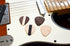 Set of four hardwood guitar picks by Pinwheel, showing different natural wood grain patterns on a plain background.