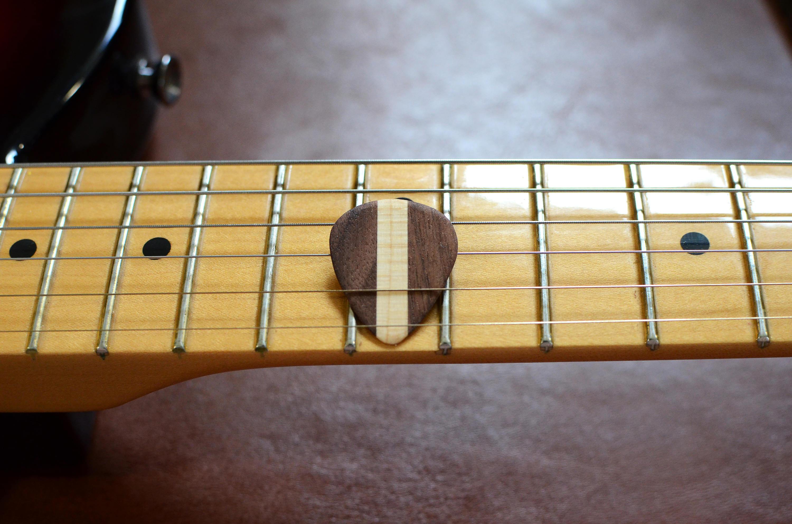 Set of four hardwood guitar picks by Pinwheel, showcasing natural wood grain and varied shapes for musical use.
