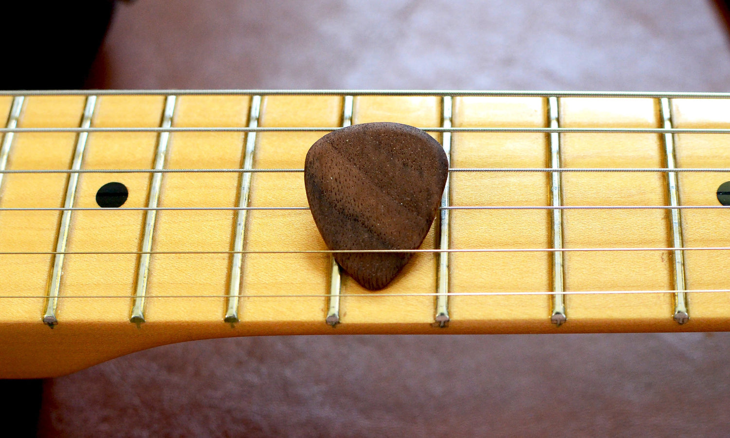 Set of four hardwood guitar picks by Pinwheel, showcasing smooth, natural wood finish and varied shapes for musical use.