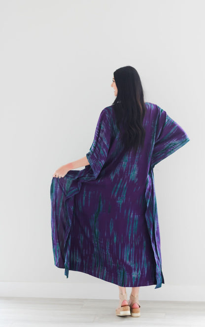 Purple tie-dyed maxi kaftan dress by Erin Pontus featuring a flowing silhouette and vibrant color, perfect for elegant wear.