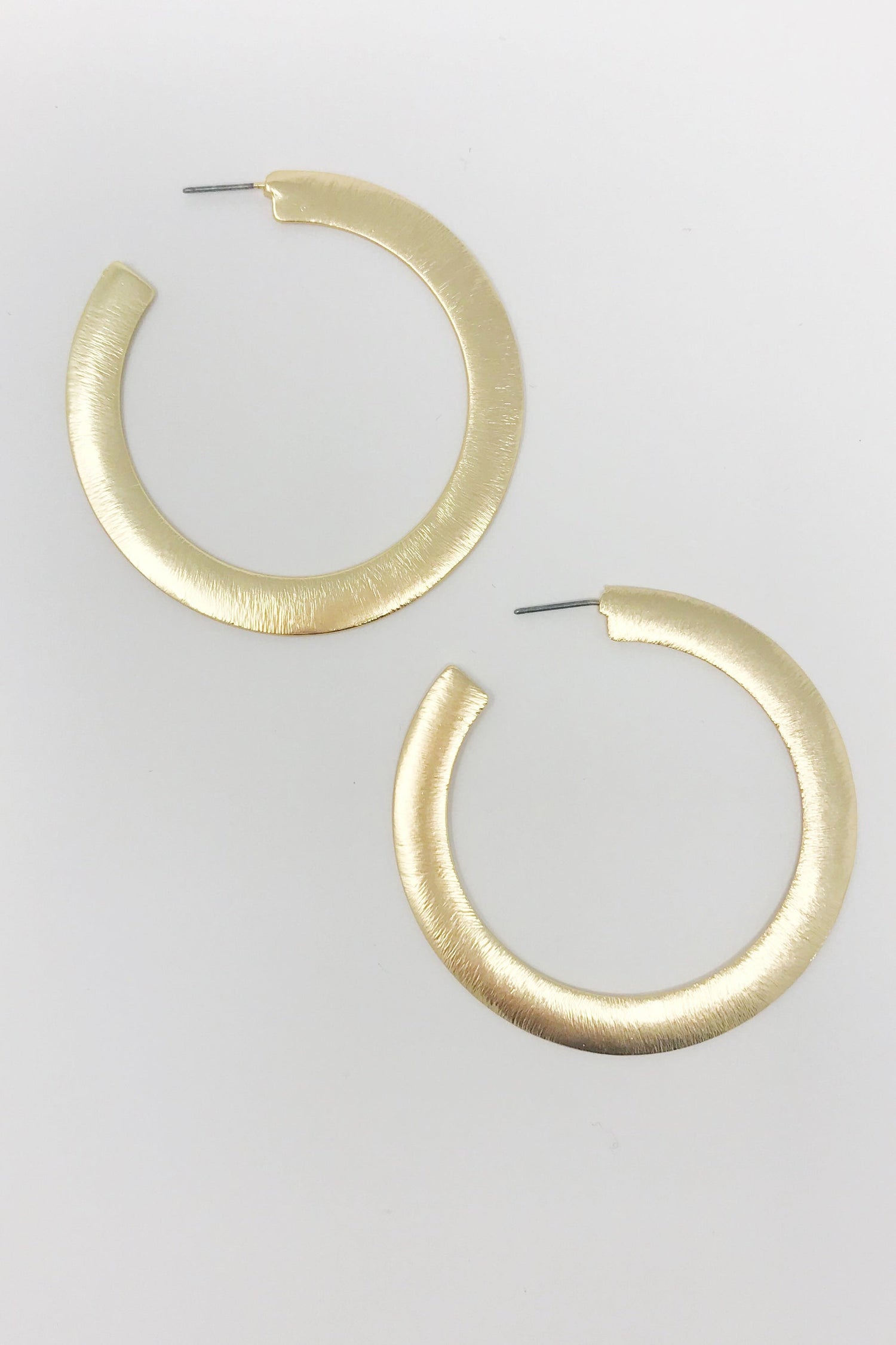 Fuchsia Hercules Alma thick gold metal hoop earrings with a flattened design, stylish jewelry accessory for women.