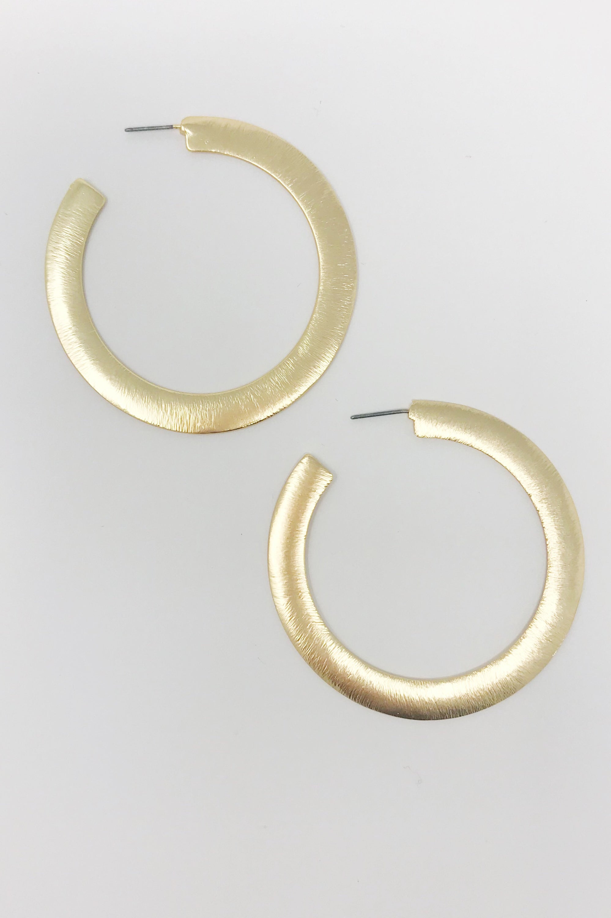 Fuchsia Hercules Alma thick gold metal hoop earrings with a flattened design, stylish jewelry accessory for women.