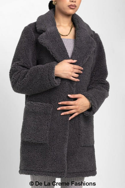 Rose Eleusis Jacqueline oversized teddy coat hanging on a clothing rack, showcasing its plush, warm design and cozy texture.
