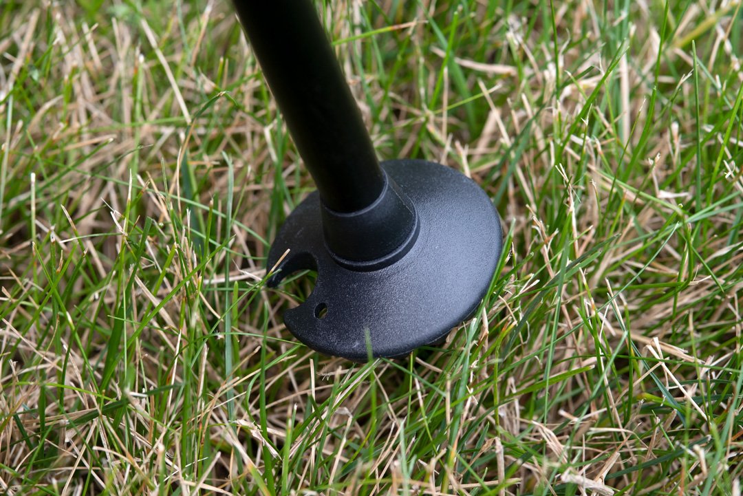 Triangulum trekking poles with 50mm mud and snow baskets, shown in grass, designed for hiking and outdoor camping activities.