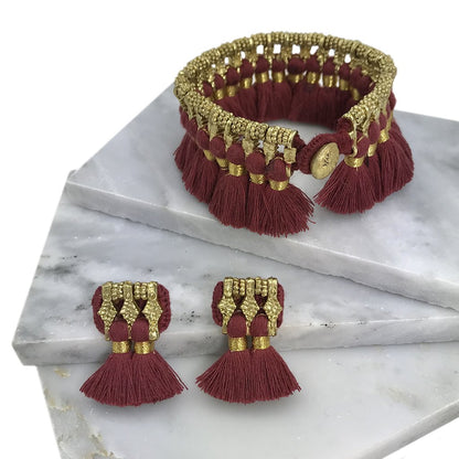 Red gold Kyra tassel bracelet by Ariel featuring gold tassels and a sleek bracelet design, perfect for stylish accessories.