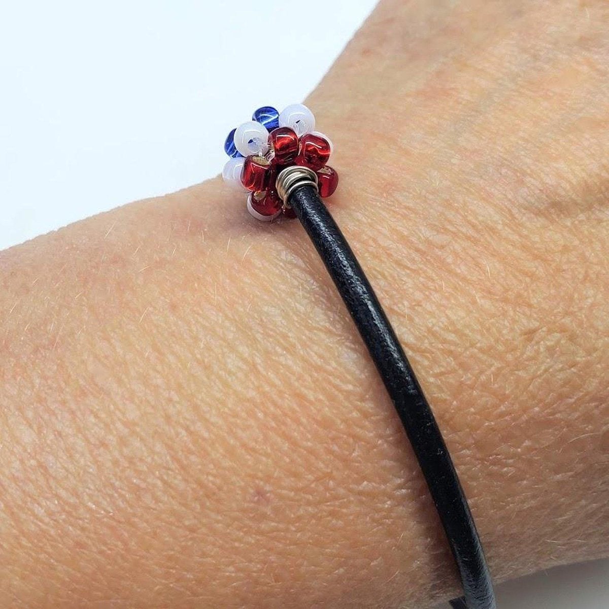 Red, white, and blue beaded leather bracelet by Blue Crius featuring patriotic design and adjustable fit.