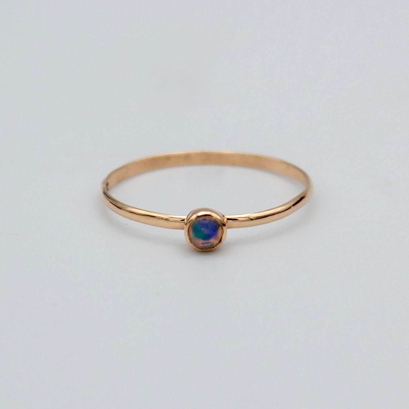 Dainty Ethiopian opal bezel ring in 14k gold-filled with delicate design, showcasing a vibrant, iridescent gemstone.