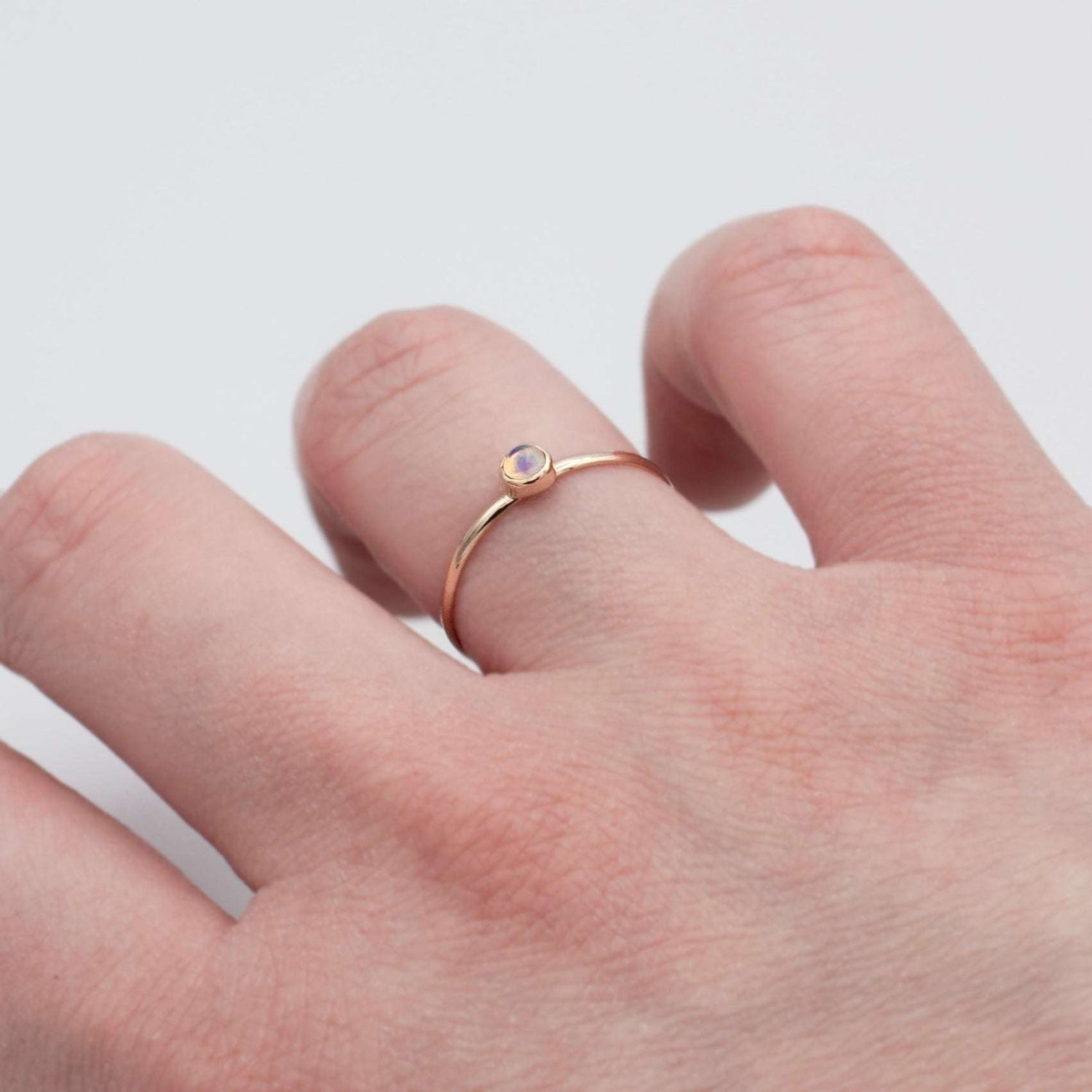 Dainty Ethiopian Opal bezel ring in 14k gold filled with a smooth band, showcasing vibrant opal in a jewelry and watches image.