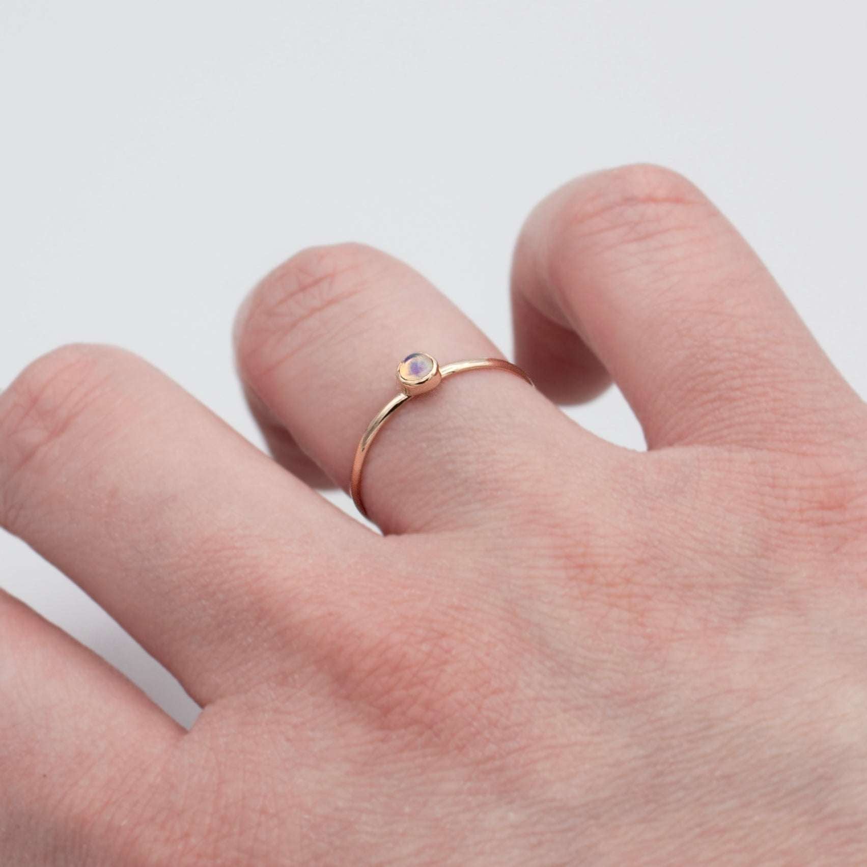 Dainty Ethiopian Opal bezel ring in 14k gold filled with a smooth band, showcasing vibrant opal in a jewelry and watches image.