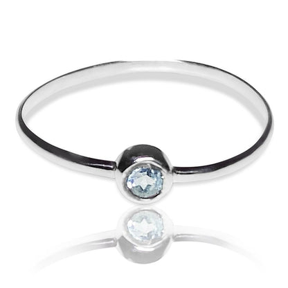Sterling silver ring featuring a dainty blue topaz solitaire tube setting, designed by Grey Clymene.