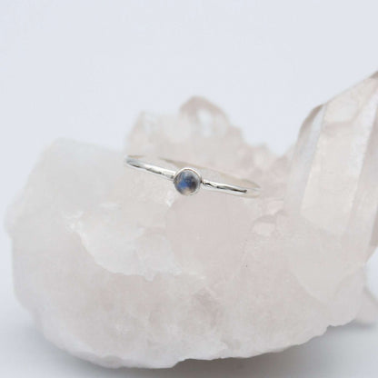 Dainty rainbow moonstone round bezel sterling silver ring from Grey Clymene featuring a smooth, polished gemstone setting.