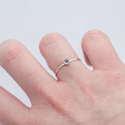 Sterling silver ring with a round rainbow moonstone bezel setting, dainty and elegant jewelry design.