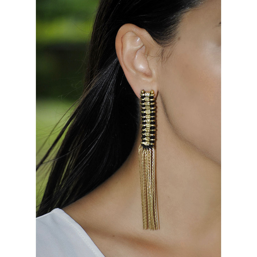 Ariel Temple Tassel Earrings with slate and salt-colored fringes hanging from gold-tone hooks.