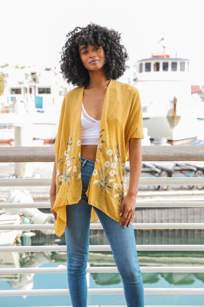 Mustard Spring Daisy Kimono by Periwinkle Aether, lightweight blouse with floral pattern, worn open over casual outfit.