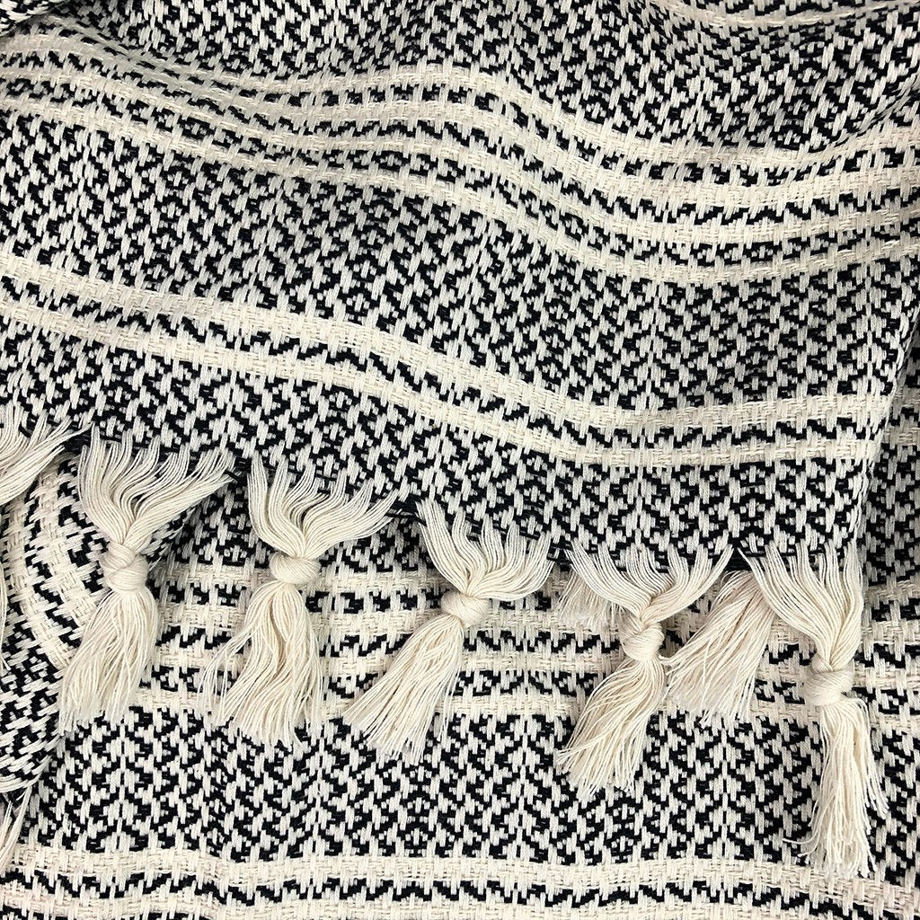 A woven Turkish throw blanket with colorful striped pattern, styled as home decor on a sofa.