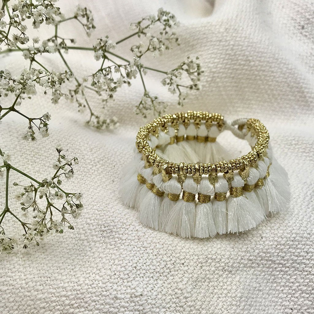 Ariel Kyra tassel bracelet with white fair trade fabric tassels and metal cuff design, stylish and eco-friendly jewelry accessory.